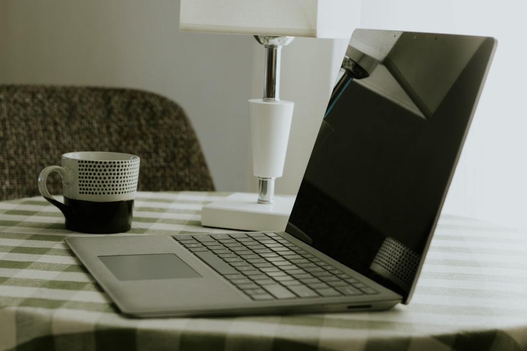 Laptop and coffee mug on a checkered tablecloth.